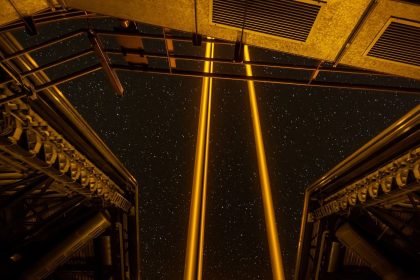 A telescope silhouetted against a starry night sky