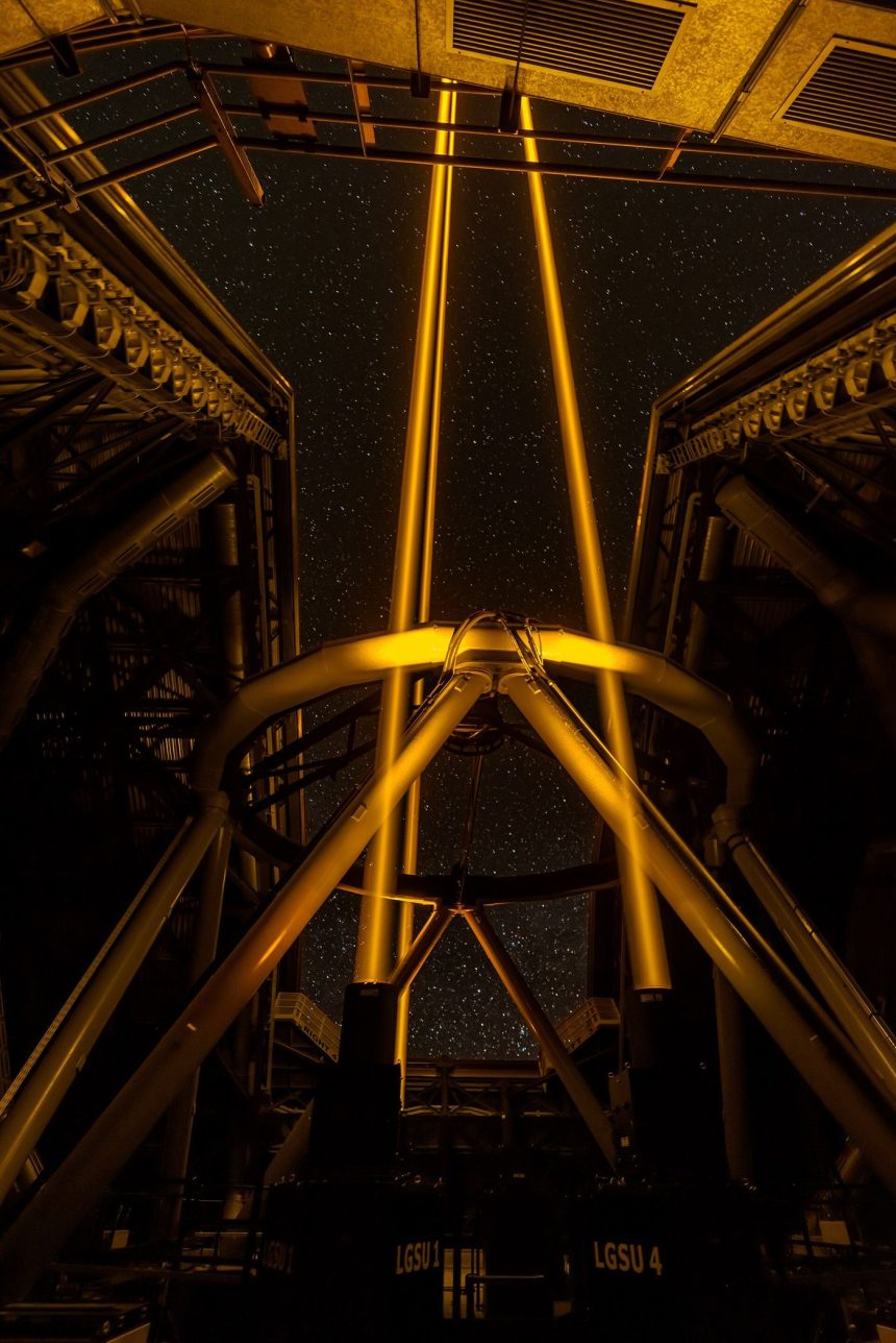 A telescope silhouetted against a starry night sky