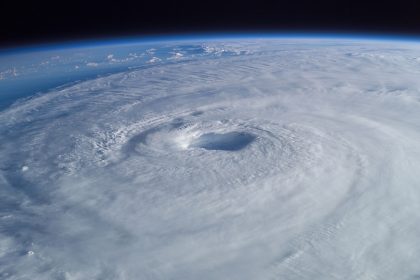 A weather satellite orbiting above Earth with swirling cloud systems below