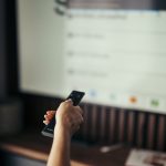 A viewer holding a remote control while watching a streaming service on TV