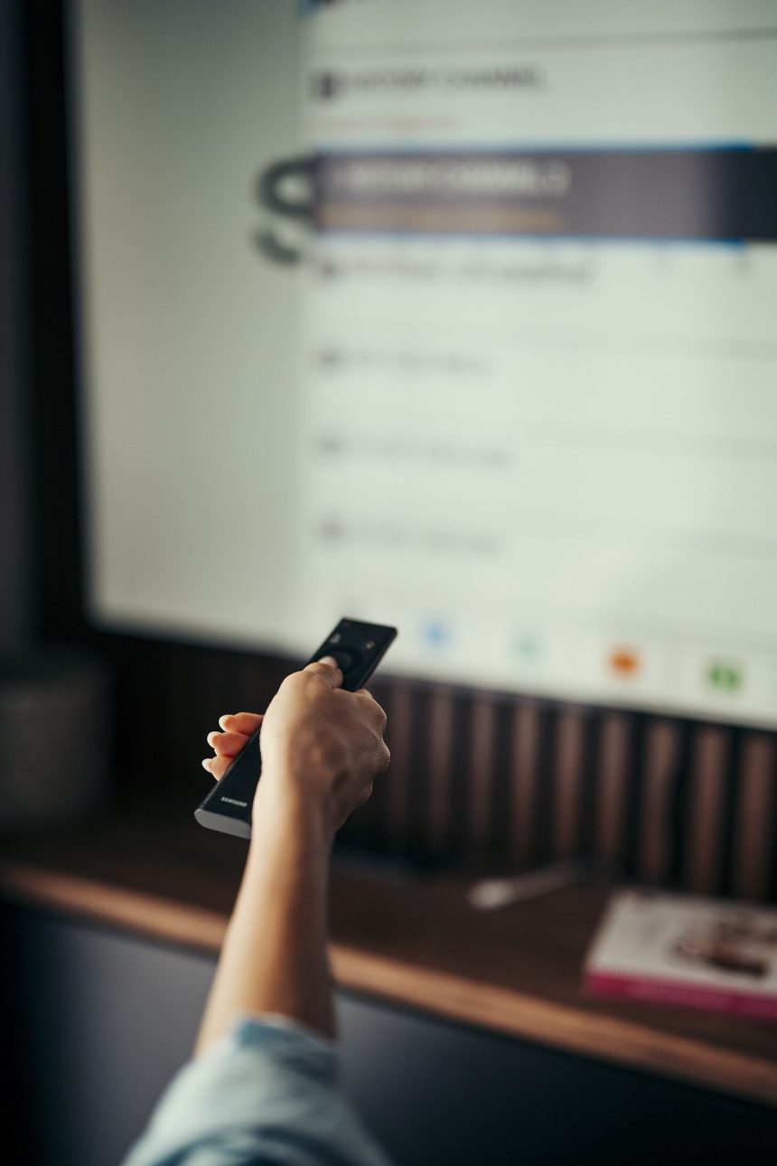 A viewer holding a remote control while watching a streaming service on TV